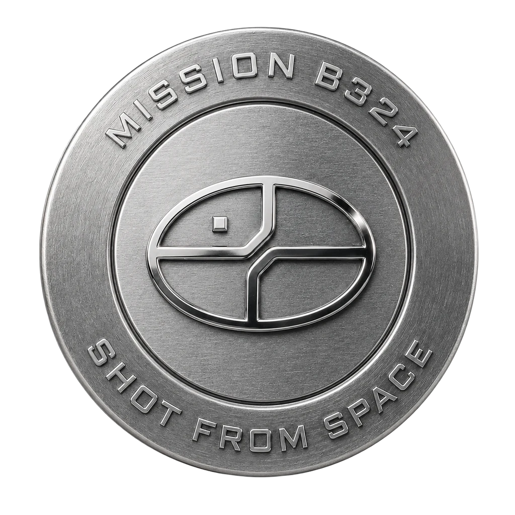 A render of a brushed aluminium mission badge, the mark raised at its centre.